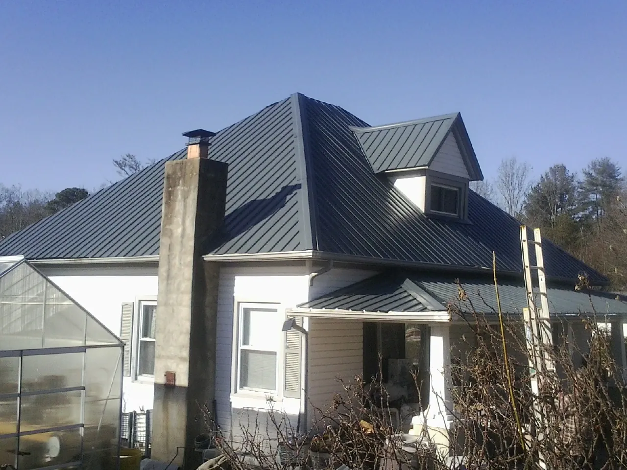Dark blue standing seam metal roof on a white farmhouse with dormer — Slate & Tile Roof Repair by Roofing Brothers in Chambersburg