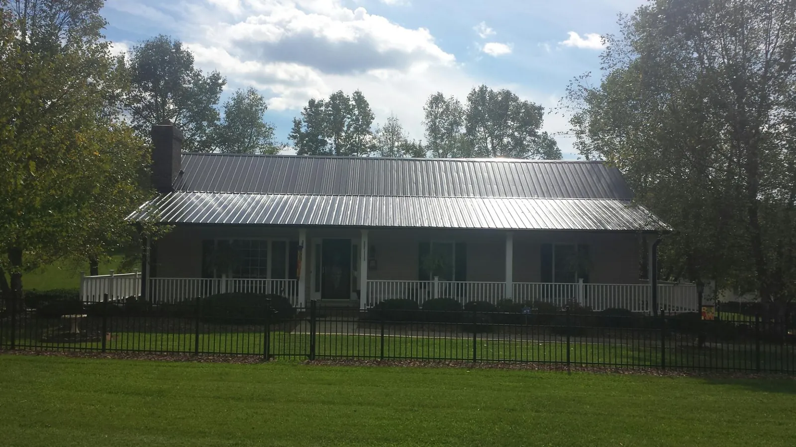 Gray metal roof on a brick ranch with a full width front porch — Gutter Guard Installation work by our crew in Chambersburg