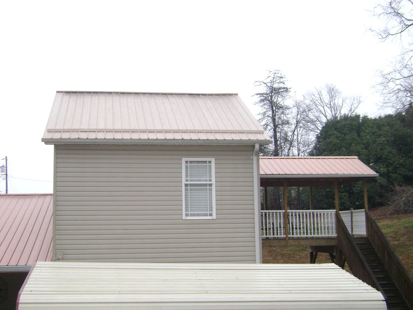 Tan metal roofs on a two story addition and attached porch, from a Roof Replacement job in Chambersburg