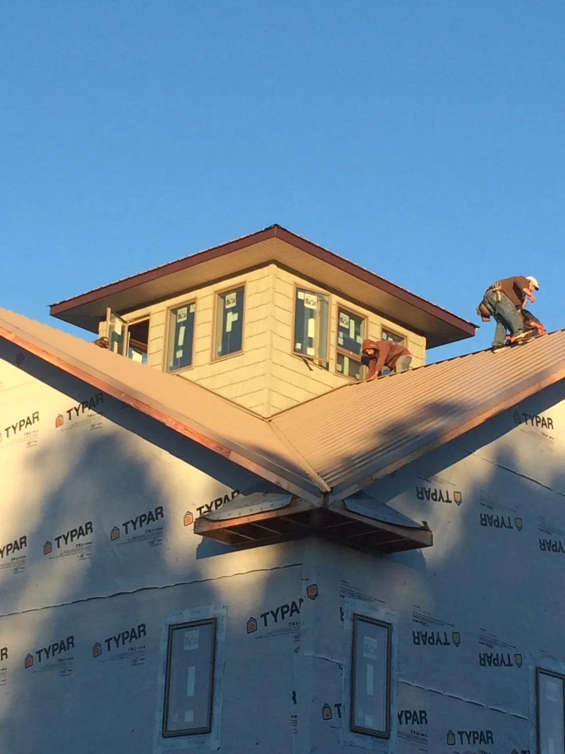 Roofers working around a rooftop cupola on a new metal roof at sunset — Roof Waterproofing in Chambersburg by Roofing Brothers